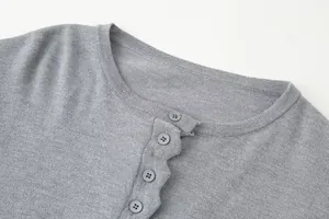 Detail shot of the ribbed round neckline and grey buttons on a knitted slim cardigan.