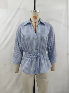 Detail of light blue striped shirt with adjustable drawstring waist and button closure