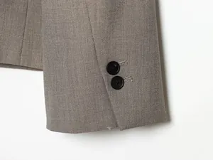 Detaillierte Makroaufnahme einer grauen Blazer-Manschette mit zwei eleganten schwarzen Knöpfen