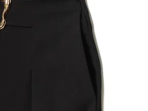 Close-up detail of side pocket and golden metal buckle on black bucket pants