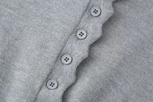 Macro detail of grey knitted cardigan showing matching round buttons and fine texture