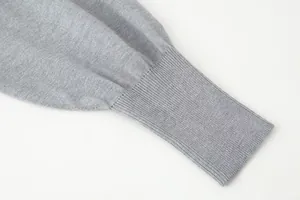 Detailed close-up view of a grey knitted cardigan sleeve with ribbed cuff texture