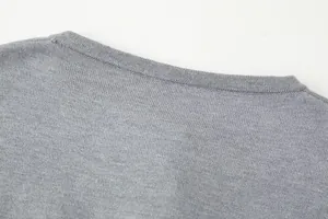 Detail view of grey knitted cardigan neckline showing high-quality stitching and fabric texture.
