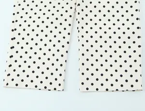 Detalle de cerca de pantalones blancos con estampado de lunares negros y dobladillos