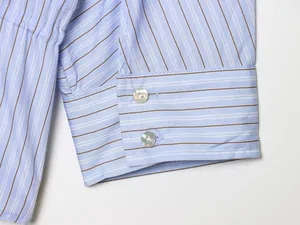 Detailed close-up of blue striped shirt cuff featuring elegant pearlescent buttons