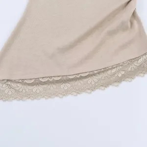 Close-up of beige knit top featuring delicate floral lace hem detail