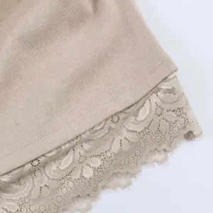 Close-up detail of elegant floral lace hem and ribbed fabric on a beige casual top