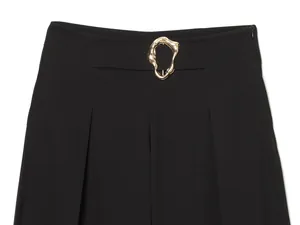Close-up of elegant black wide-leg trousers featuring a unique gold metal buckle