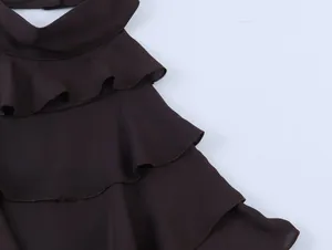 Detailopname van een stijlvolle donkerbruine georgette haltertop met elegante rucheslagen