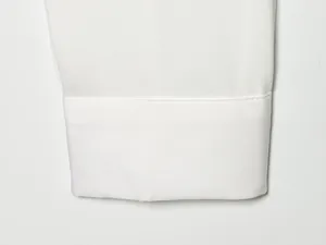Detalle macro de un puño de camisa blanca con costuras impecables y textura de tela.