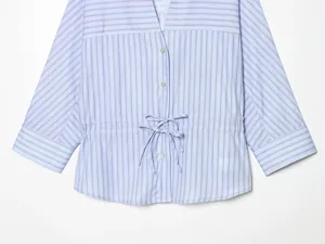 Close-up detail of a light blue striped women's shirt with waist tie bow