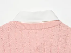 Primer plano detallado de un suéter rosa de punto de ochos con cuello de camisa falso blanco