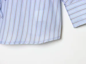 Close-up of blue striped shirt hem and cuff showing detailed stitching and fabric texture.