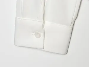 Vista macro detallada de un puño de camisa blanca con botón y costuras de calidad