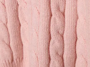Vista macro detallada de un jersey rosa de punto de ochos con texturas intrincadas