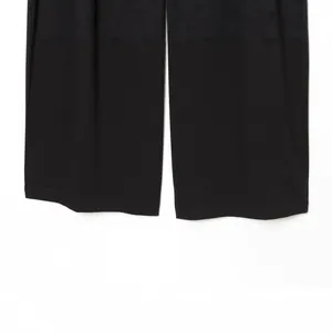 Detail shot of black wide-leg trousers showing straight leg hems on white background.