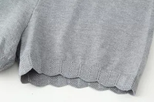 Close-up detail of the scalloped hem on gray knitted shorts showing chevron texture pattern