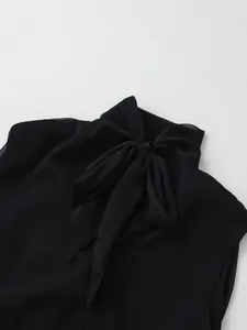 Detalle de una blusa negra sin mangas con cuello alto y un elegante lazo decorativo