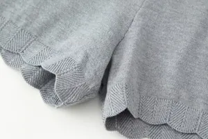 Close-up detail of the scalloped hem and chevron knit pattern on grey knit shorts
