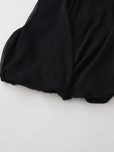 Vista detallada de la tela plisada negra y el dobladillo de la blusa sin mangas