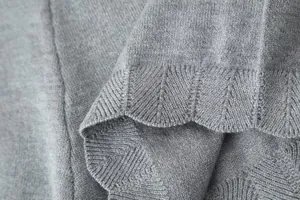 Detailed view of grey knitted fabric featuring a scalloped hem with chevron pattern