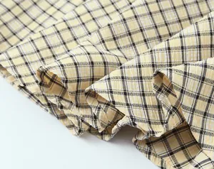 Detailed macro view of yellow and black checkered dress fabric with crinkle seersucker texture