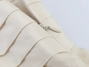 Close-up of hidden zipper and layered fabric detail on ivory asymmetric skirt.