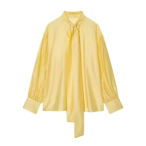 Detail van een lichtgele satijnen blouse met een zeer elegante strik aan de hals.
