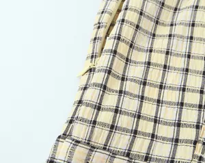 Close-up detail of the invisible side zipper on a yellow checkered midi dress fabric