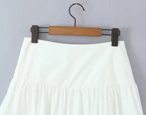 Close-up of the pleated waistline and tiered details on a white mini A-line skirt.