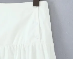 Close-up of white mini A-line skirt featuring stylish round buttons and pleated hem