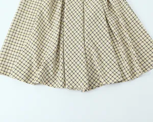 Detail view of a yellow and black plaid midi dress hem showing fabric texture