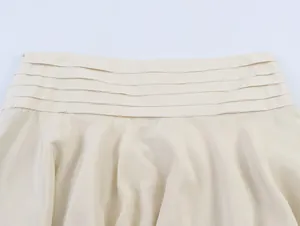 Close-up detail of cream layered pleated waistband on stylish women's skirt