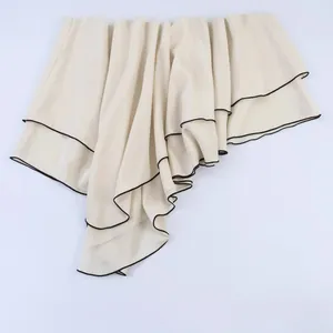 Fashionable off-white layered asymmetric skirt with black piping detail and soft drape
