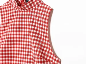 Detailed view of a red and white checkered sleeveless high-neck top showing fabric texture