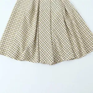 Close-up of the pleated hem on a stylish yellow and black checkered plaid midi dress