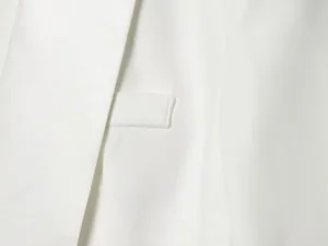 Macro detail of white tuxedo blazer fabric showing fine stitching and texture.