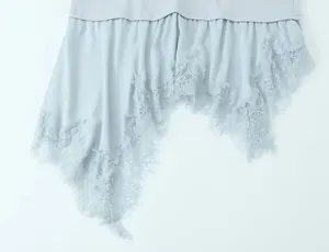 Close-up of delicate eyelash lace trim on asymmetric hemline of light blue top