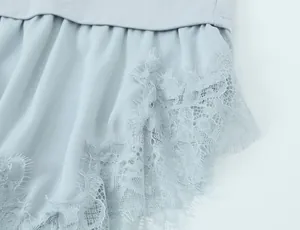 Macro close-up detail of light blue asymmetrical T-shirt featuring delicate lace trim
