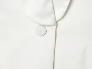 Close-up of white satin lapel and fabric-covered button detail on blazer