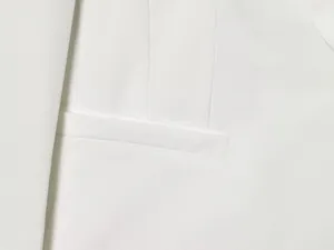 Close-up macro detail of white tuxedo jacket pocket showing premium fabric texture