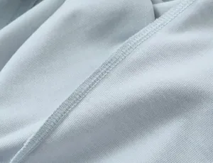 Close-up detail of light blue knitted fabric showing high-quality overlock stitching