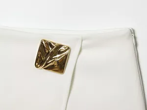 Close-up of asymmetrical white skort featuring a stylish gold irregular metal buckle