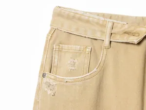 Gros plan d'un jean beige avec une taille repliée unique et des poches vieillies.