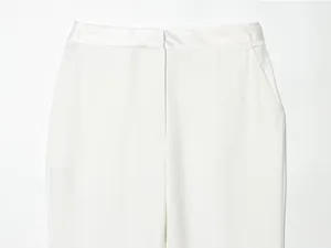 Close-up detail of white tuxedo trousers featuring a satin waistband and side pockets