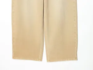 Détail macro de jambes de jean beige montrant les coutures de l'ourlet et le tissu sergé