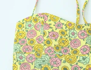 Détail d'un haut en popeline jaune avec des motifs floraux roses et menthe vifs