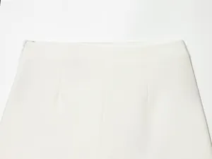 Detail view of white asymmetric culottes showing high waist and side zipper closure