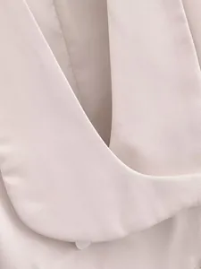 Détail macro d'un gilet de costume rose clair montrant la texture du tissu premium.
