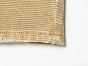 Vue macro montrant la texture du denim kaki de qualité et les détails de couture.